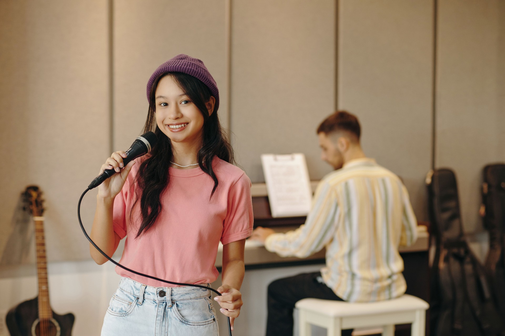 Smiling Girl Singing While Holding Microphone in Studio
